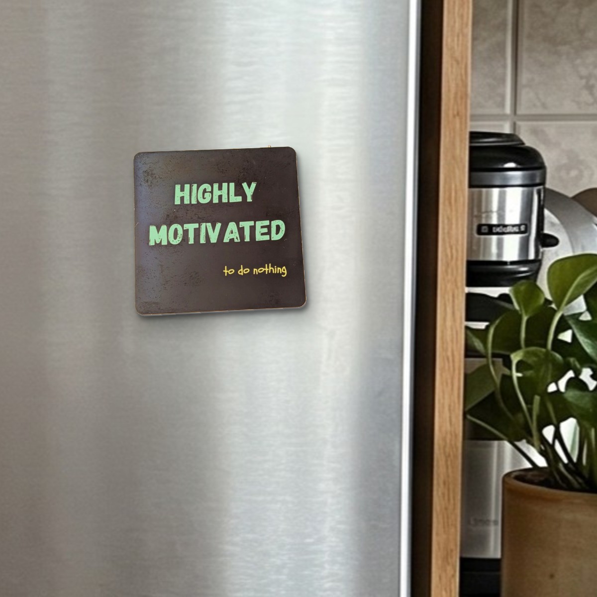 Highly Motivated (To Do Nothing) fridge magnet on a stainless steel fridge door