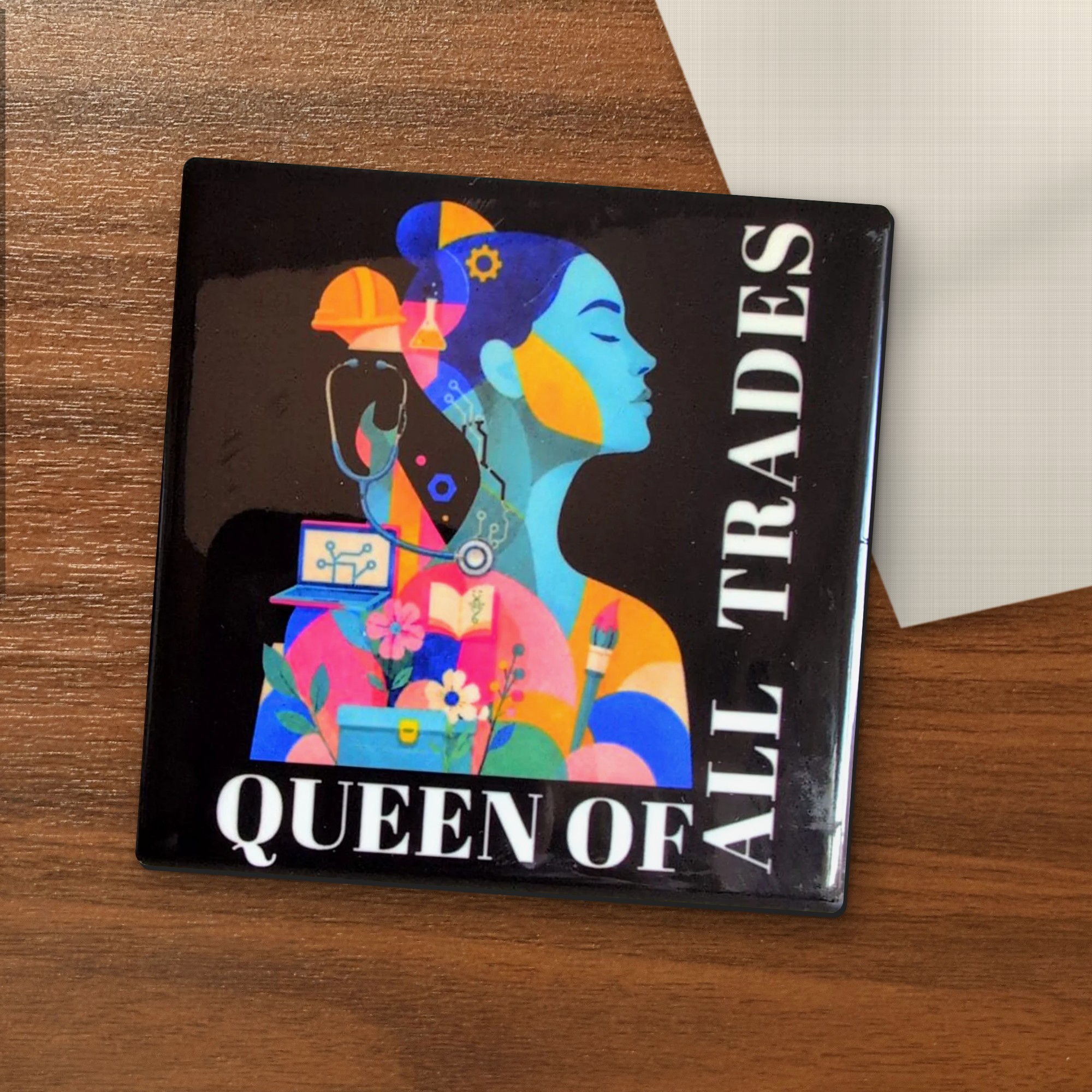 Queen of All Trades coaster on a wooden table